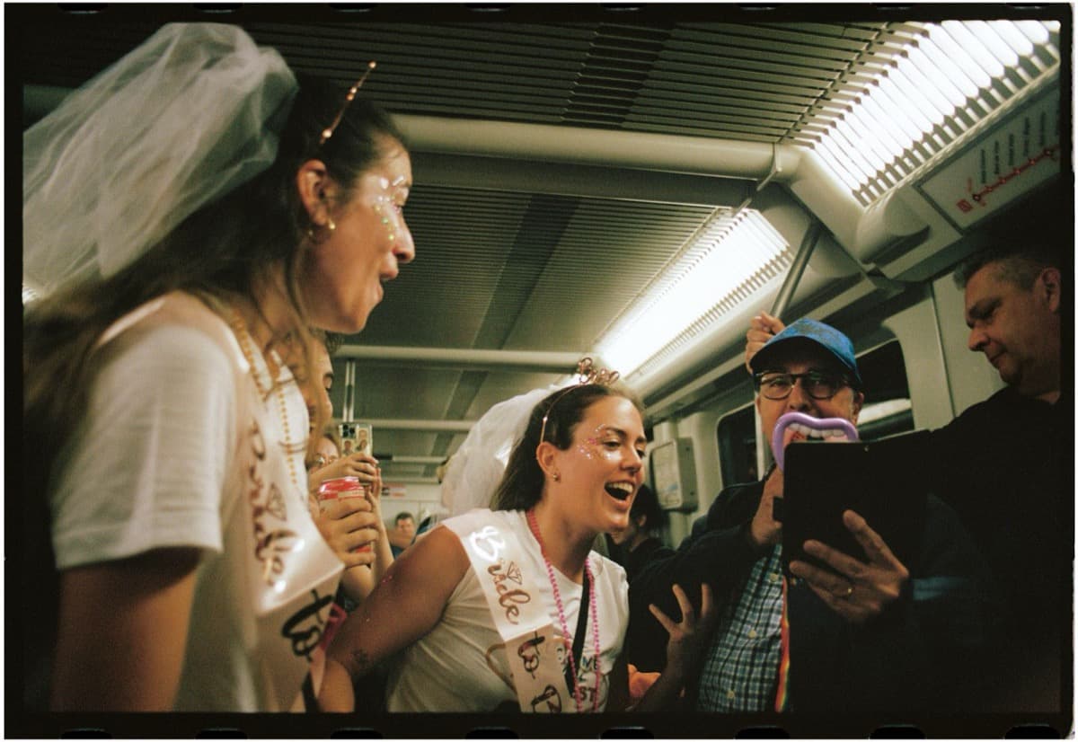 Una futura sposa col velo ride con le amiche in metropolitana, scatto su pellicola